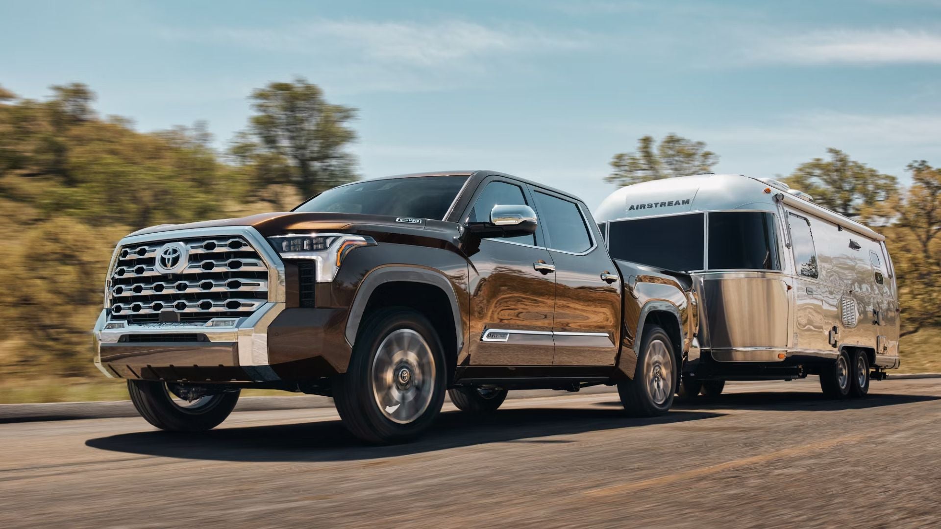 large pickup truck towing a travel trailer on a road