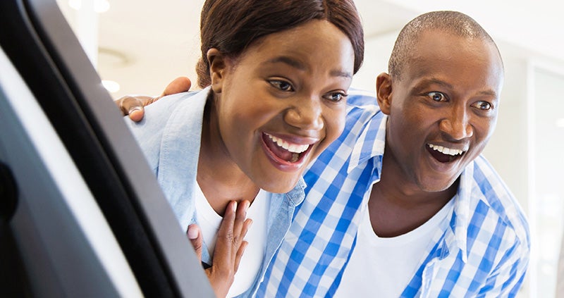 Two people leaning toward a screen with wide smiles and expressive faces